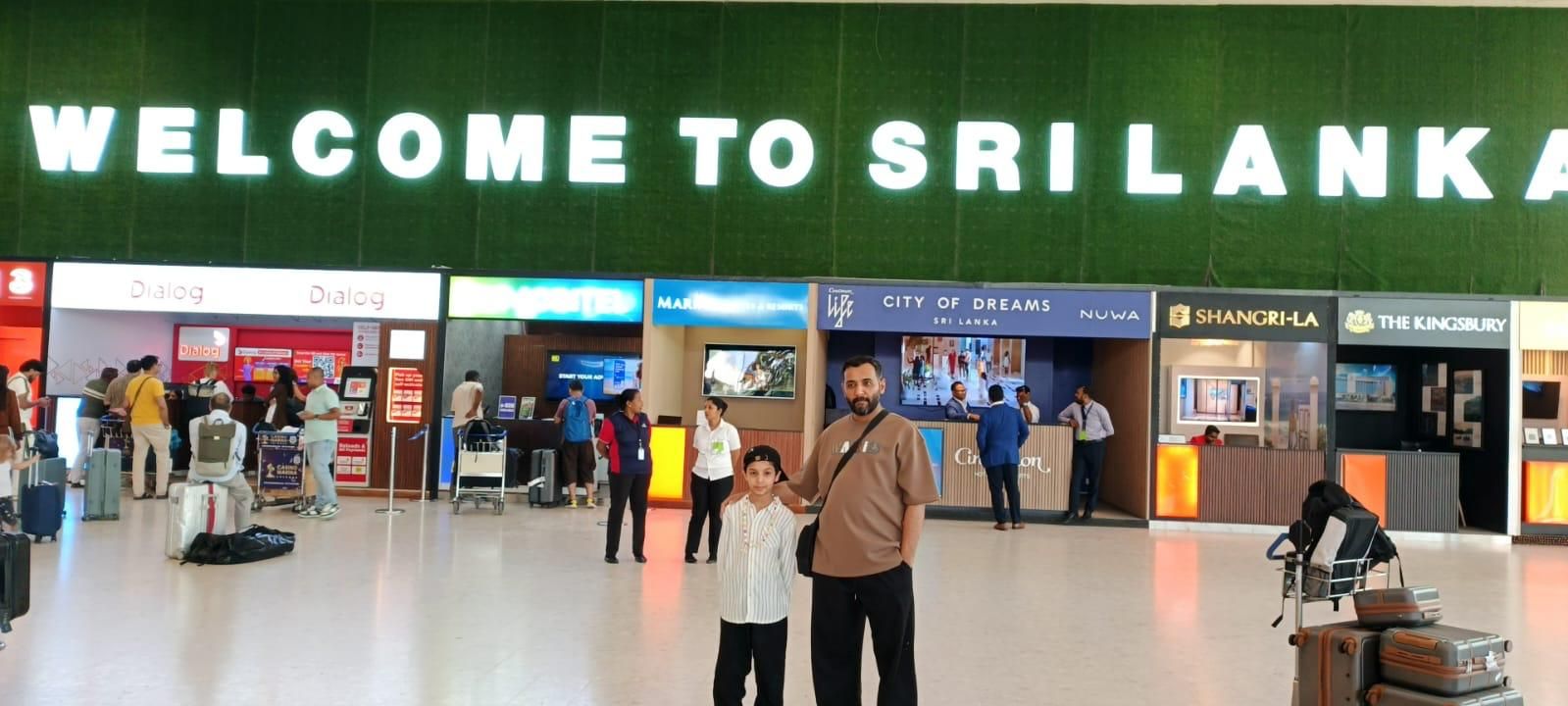 A father and son under the Welcome to Sri Lanka sign at the airport