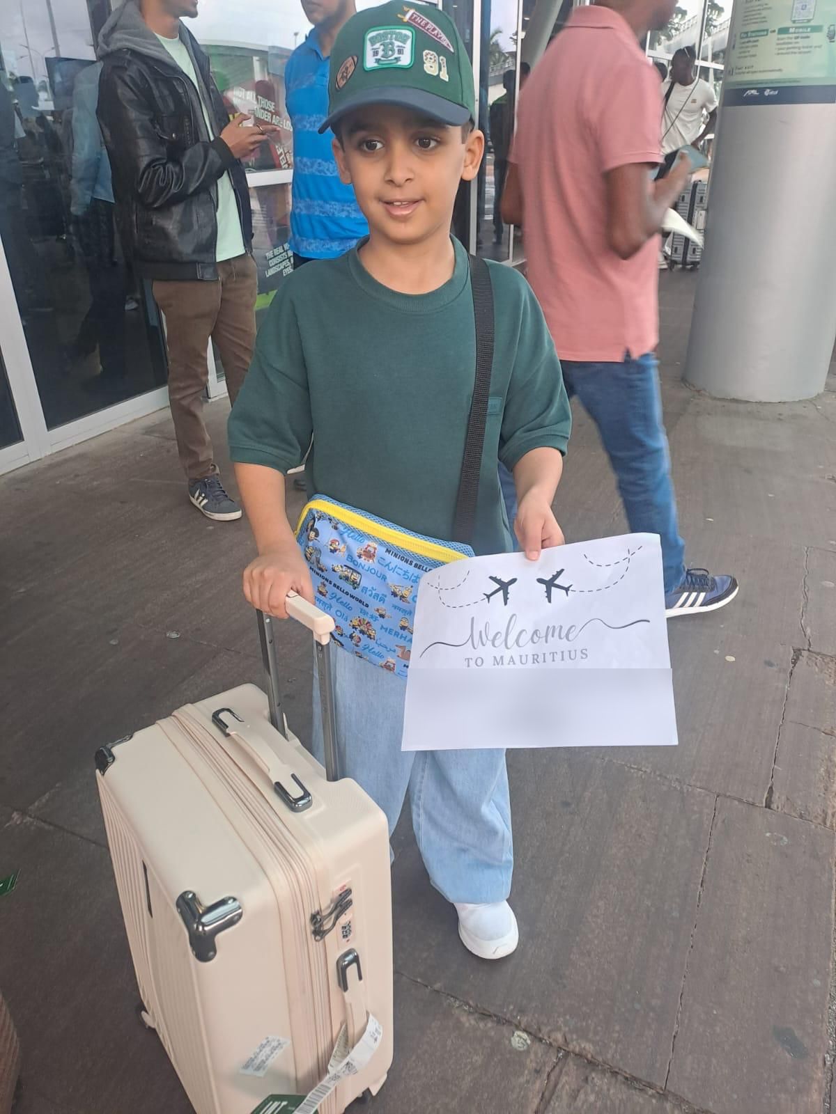 A young guest holding a Welcome to Mauritius sign with his suitcase