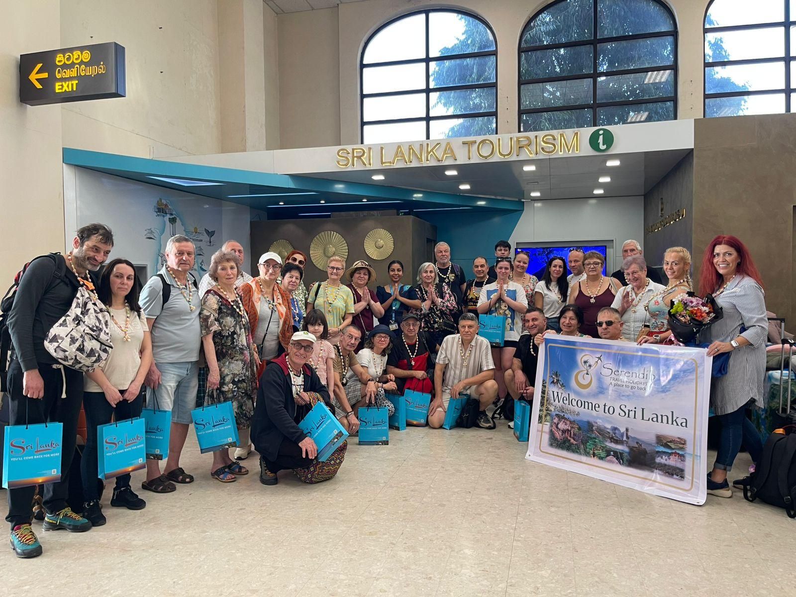 A large tour group holding a Serendib Travel Holidays welcome banner at the Sri Lanka Tourism desk, Colombo airport