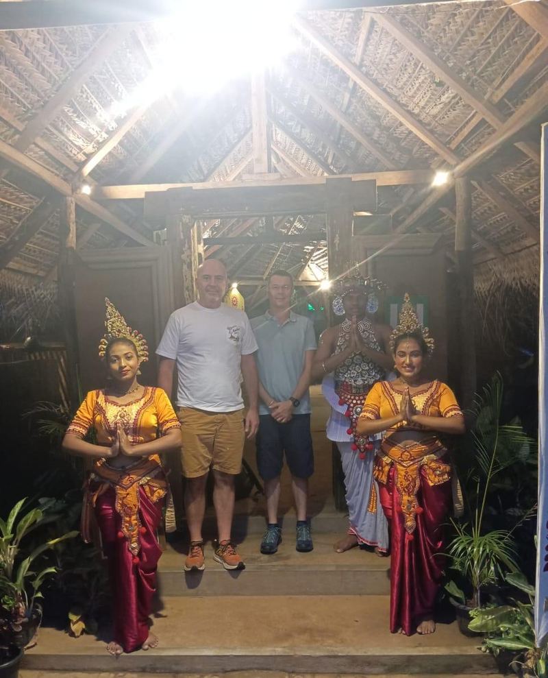 Two guests between dancers in traditional costume at an evening show