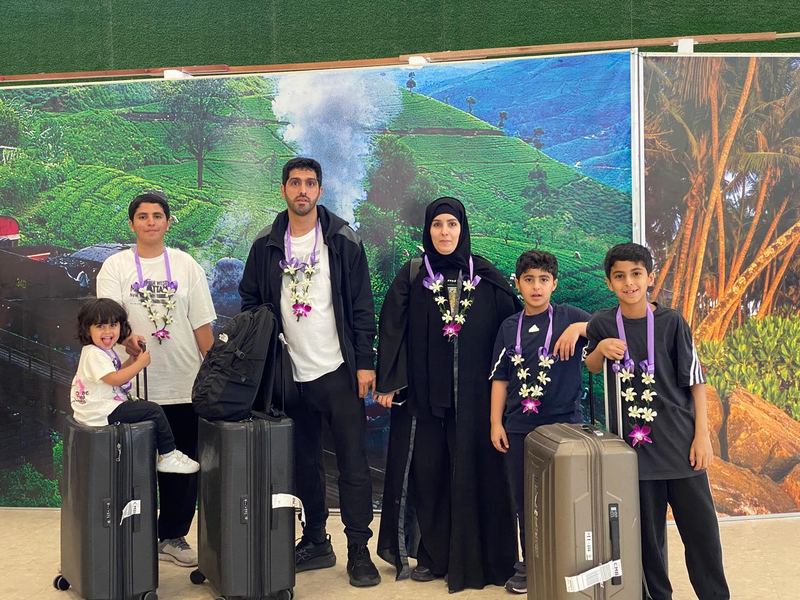 A family with orchid garlands and suitcases in the arrivals hall