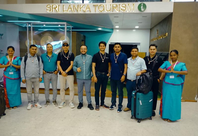 A group of men with shell garlands between hostesses at the tourism desk