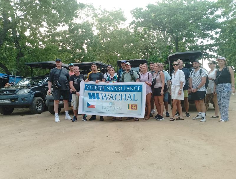 A tour group with a welcome banner in front of safari jeeps