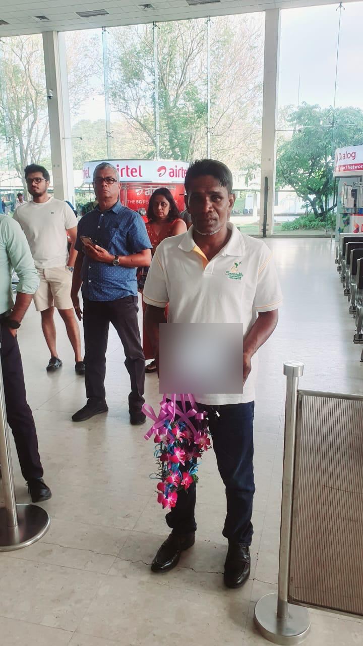 A Serendib staff member in a branded polo shirt waiting at arrivals with a welcome tablet and garland